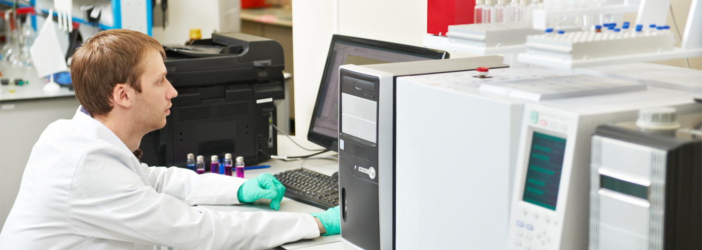 A researcher sits at a computer while working in a lab